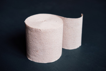 Rigid brown Soviet toilet paper) (one roll) on a dark background.