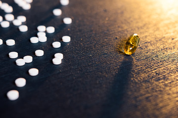 One side of white small tablets versus one tablet (fish oil). The medicine.