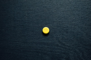 One small yellow tablet with a slot on a dark wooden background. View from above. Texture....