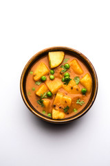 Aloo Curry Sabzi made using boiled potato with green peas. Served in a bowl or karahi, selective focus