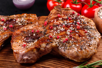 Fresh delicious juicy steak on the bones with vegetables and spices against a dark background