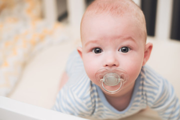 The baby lies in a crib on his tummy.