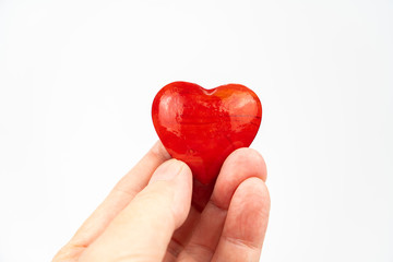 Fototapeta premium Red heart held in hand, white background and copy space