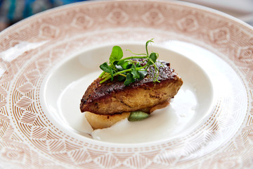 Scallops with foie gras, wasabi cream and coconut espuma on a white plate