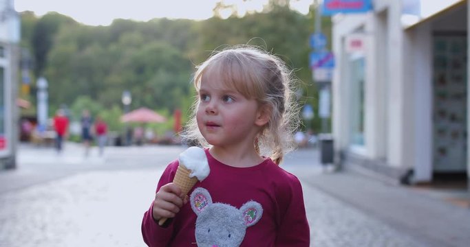 Little blond girl eating eis in the pink