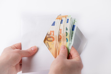 hands hold a white envelope and take out the euro on a white background, salary in an envelope, a bribe