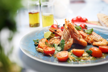 Shrimps in lemon butter sauce with cherry tomatoes. A tasty crustacean dish. A plate with an appetizing dish. Application suggestion. Culinary photography, food stylization.