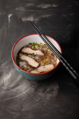 Composition with a bowl of rice noodles, meat and vegetables