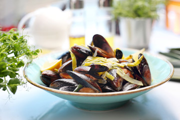 Mussels with leek and white wine. A tasty crustacean dish. A plate with an appetizing dish. Application suggestion. Culinary photography, food stylization.