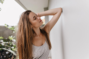 Long-haired happy woman relaxing during morning photoshoot. Outdoor photo of positive european girl posing with eyes closed.