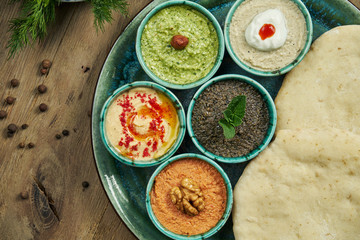 Classic eastern snacks with pita - meze. Set in small bowl - Hummus, hot pepper paste often with walnuts, yogurt, eggplant paste.
