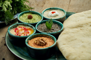 Classic eastern snacks with pita - meze. Set in small bowl - Hummus, hot pepper paste often with walnuts, yogurt, eggplant paste.