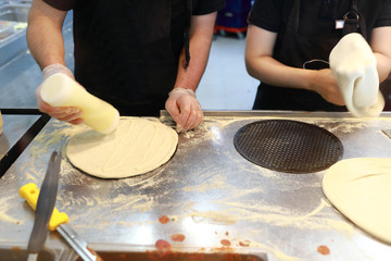 Two men preparing pizza for baking
