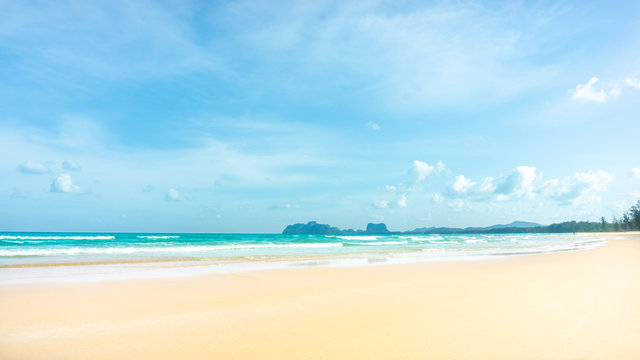 Clean white beach golden brown sand and blue sea under clear blue sky in a sunny day, mountain on background