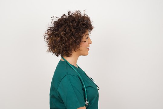 Profile of smiling doctor woman with healthy pure skin,  has contemplative expression, ready to have outdoor walk, isolated over white studio wall with copy space.