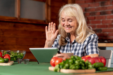 Elder woman in kitchen using tablet