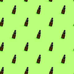 Pattern of herbal oil bottle aroma dropper on green mint color background.