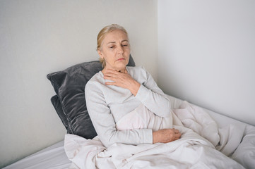 Coronavirus disease (COVID-19) symptoms are a runny nose, sore throat, cough, and fever.Senior woman sick of coronavirus viral infection spreading corona virus. Patient lying in bed at home quarantine