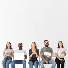 Young friends on chairs using modern devices