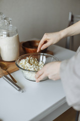 female hand prevents a golden.fork with a white cup on a white table cottage cheese in a cup