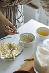 female hand prevents a whisk with a white cup on a white table cottage cheese in a cup
