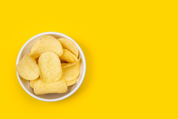 Patatas fritas dentro de un cuenco blanco sobre fondo amarillo brillante liso y aislado liso. Vista...