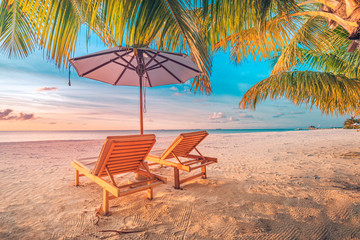 Relaxing sunset beach, summer vacation and holiday concept. Beach sunset view loungers and umbrella. Luxury travel landscape, exotic nature background. Paradise island view