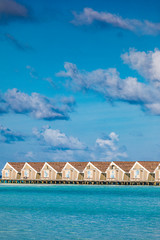 Water villas in the ocean with steps into turquoise lagoon. Exotic travel and summer vacation vertical banner design