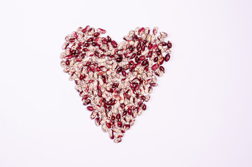 Dry purple beans for vegans in the form of a heart on a white background copy space