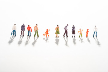 Close up view of row of people figures on white surface with shadow