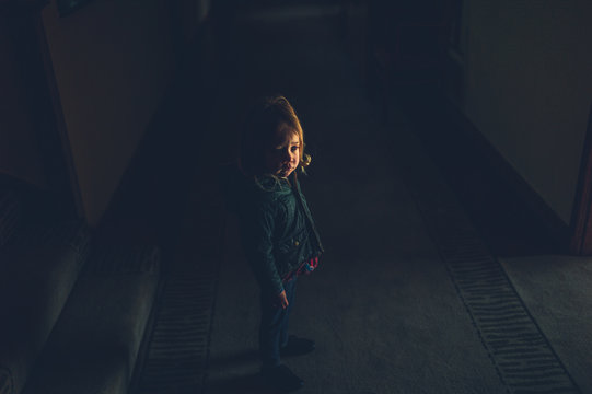 Little preschooler standing in dark corridor