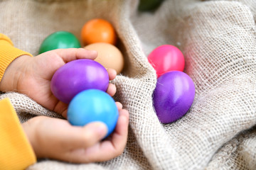 children hands holding easter eggs on burlap background