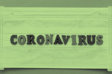 Coronavirus inscription from letters on a medical white mask on a blue background