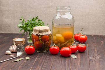 Glass jar of canned tomatoes, fresh tomatoes, green parsley, garlic .