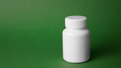white jar with pills on a green background