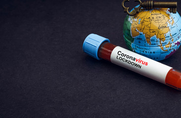 CORONAVIRUS LOCKDOWN text with world globe, key and Blood test vacuum tube on black background. Covid-19 or Coronavirus Concept