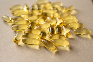 scattering of fish oil pills on a light gray background. translucent gelatin capsules