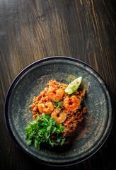 Fried rice with shrimp and vegetables in plate on wooden table background