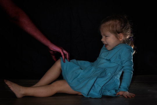 a little girl sits on the floor in a dark room, a terrifying scary purple hand grabbed her leg, the girl screams in horror and fear. nightly children's fears and fear of being alone