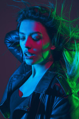Beautiful woman's portrait with blowing, flying hair on dark studio background in colorful green, red, blue neon light. Concept of human emotions, ad. Trendy colors. Fashion and beauty in motion.