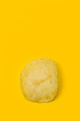 Una patata frita ondulada sobre fondo amarillo brillante aislado. Vista superior. Copy space