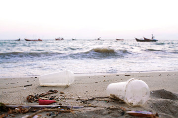 Fototapeta na wymiar Dirty sand shore with plastic glass 