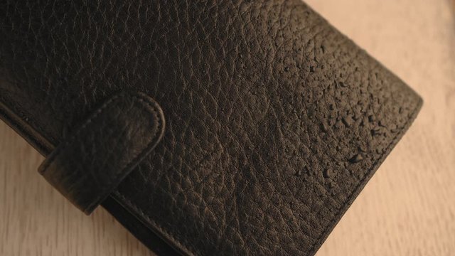 Drops of water splashing onto a part of black texture leather wallet. Waterproof and protection leather products. Slow motion shots