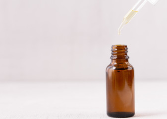 cosmetic pipette with drops of oil. Transparent brown bottle. Close up, copy space. Grey background. Health, skin, body care. Aromatherapy. 