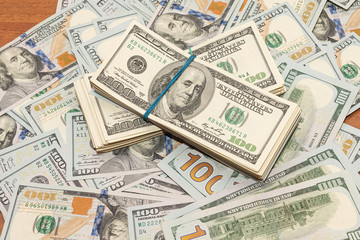 Many hundred dollar bills on wooden table background texture. bundles of money scattered on the office desk. wealth and income concept