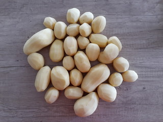 A pile od peeled potatoes on a wooden table