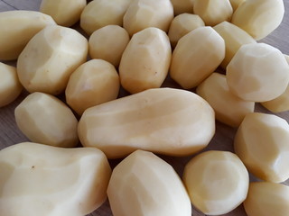 A pile od peeled potatoes on a wooden table