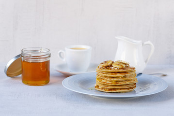 Delicious banana pancakes on a blue plate with honey and nuts. Coffee with milk. Close up. Healthy, sweet, eating, breakfast, snack. Vegetarian. Dessert, snack. 