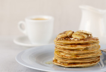 Delicious banana pancakes on a blue plate with honey and nuts. Coffee with milk on background. Close up. Selective focus. Healthy, sweet, eating, breakfast, snack. Vegetarian. Dessert, snack. Recipe.