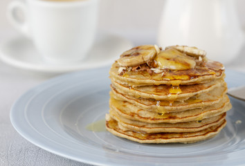 Delicious banana pancakes on a blue plate with honey and nuts. Coffee with milk. Close up. Healthy, sweet, eating, breakfast, snack. Vegetarian. Dessert, snack. Recipe